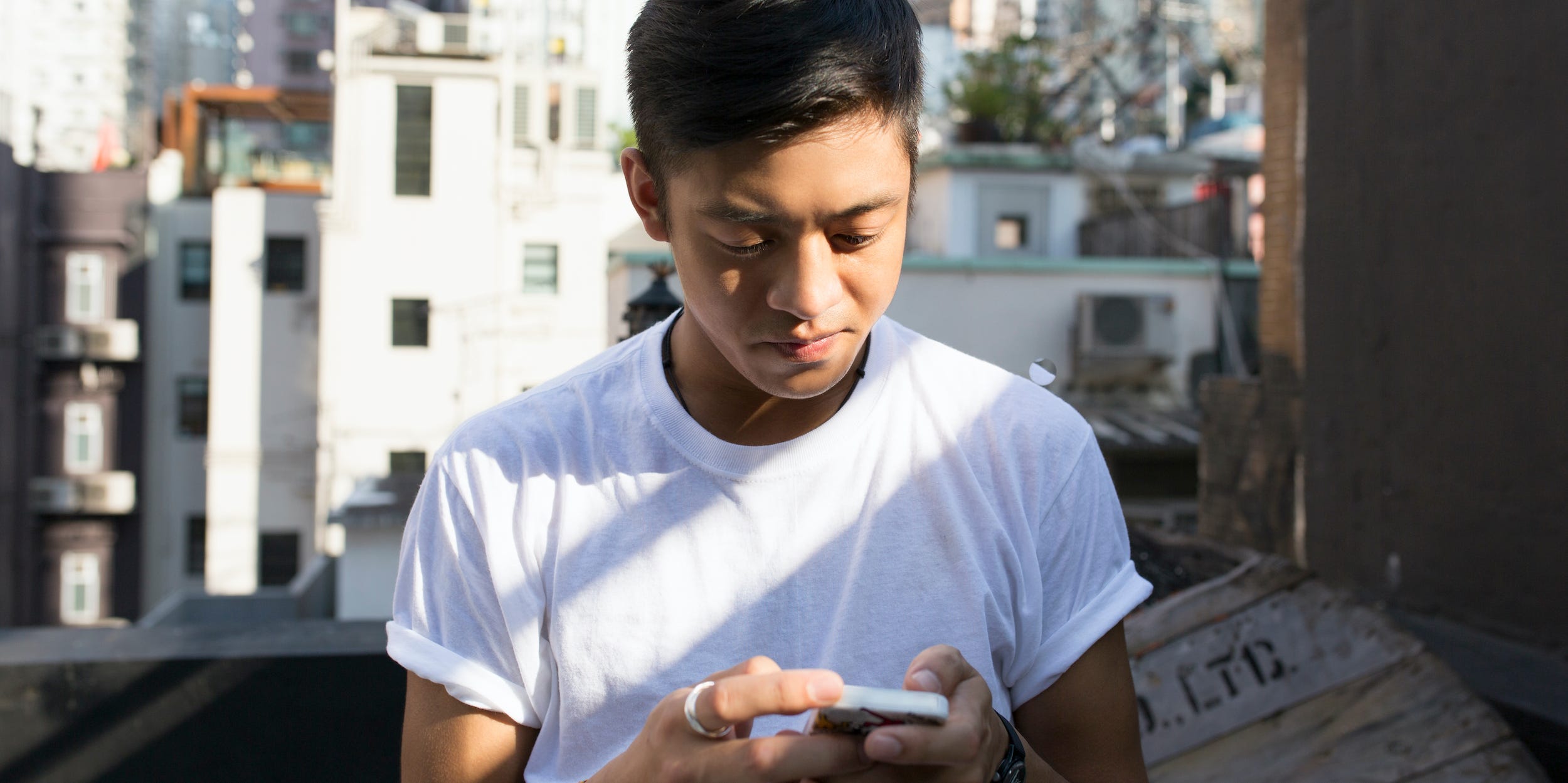 junger Mensch SMS auf dem Smartphone in der Stadt